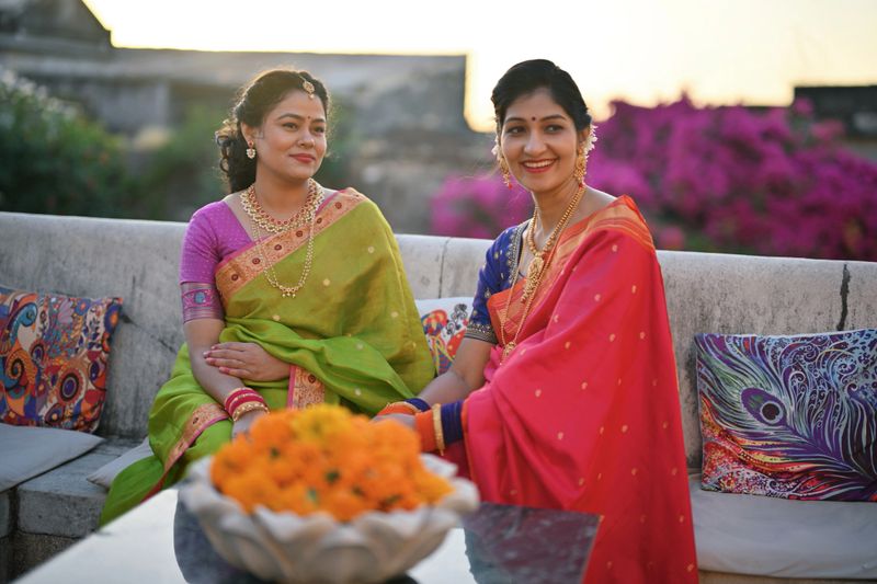 Two beautiful Indian women in saris talking to each other sitting on a marble bench in a palace in Rajasthan