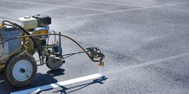 Machine painting white lines on asphalt for road marking.