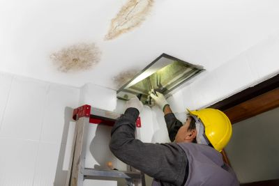 Contractor in protective gear working on a ceiling during asbestos abatement