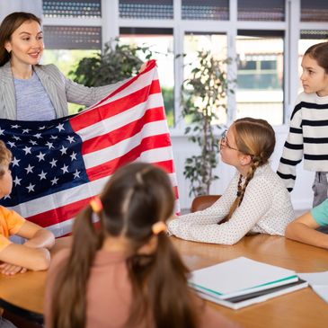 Teacher showing the American flag to attentive children in classroom.