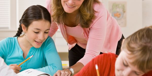 Teacher helping students with their schoolwork in a classroom.