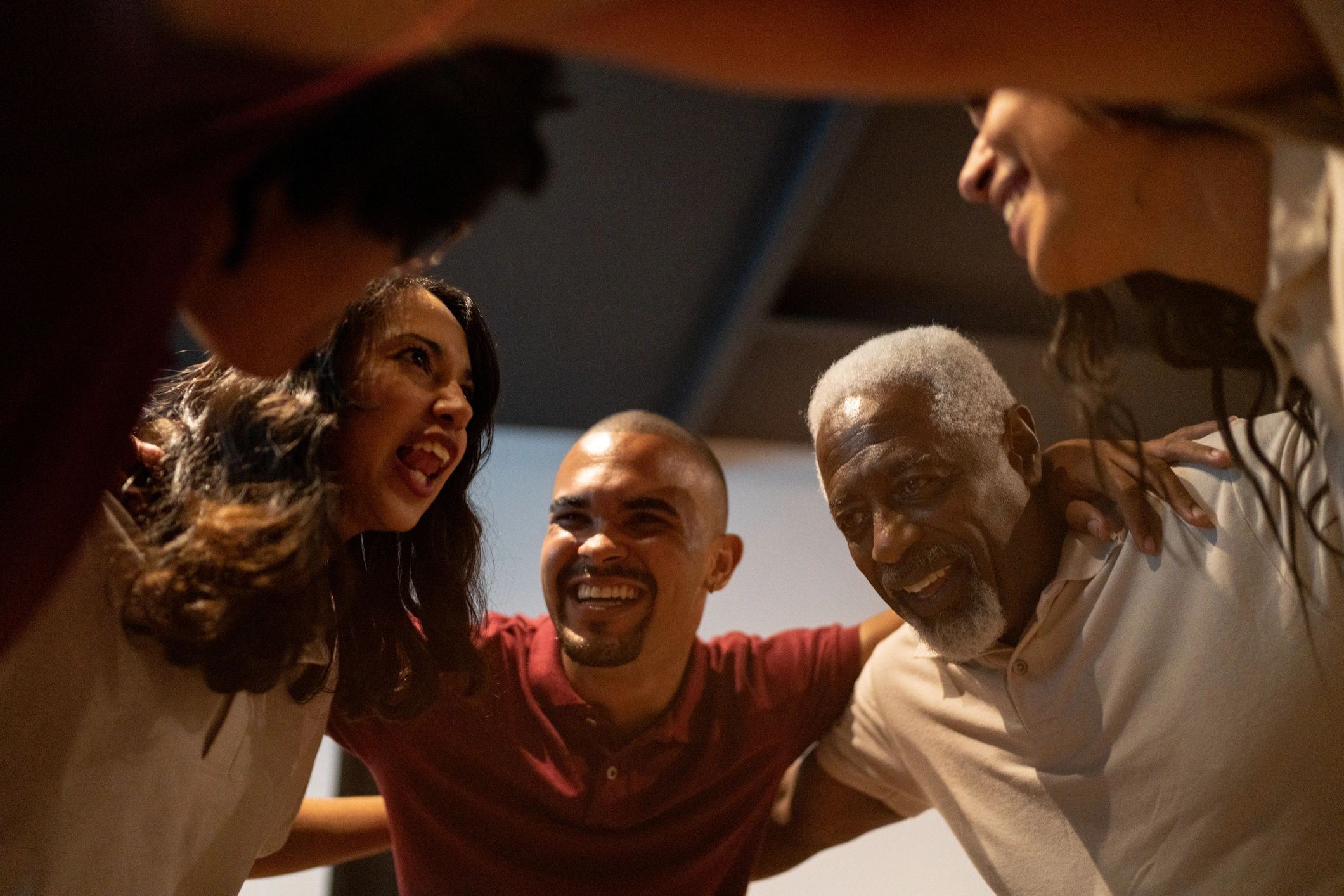 A diverse group of friends happily embracing in a circle indoors.