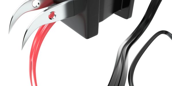 Close-up of a black electric plug with sharp, claw-like metal prongs emitting red light.