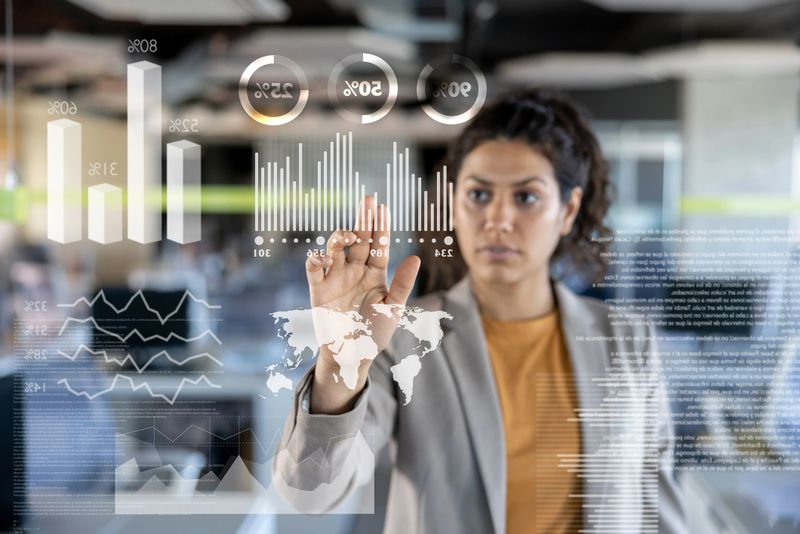 Successful Latin American business woman looking at the market data on an interactive screen