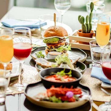 A gourmet burger with avocado and fresh drinks on a stylish table.