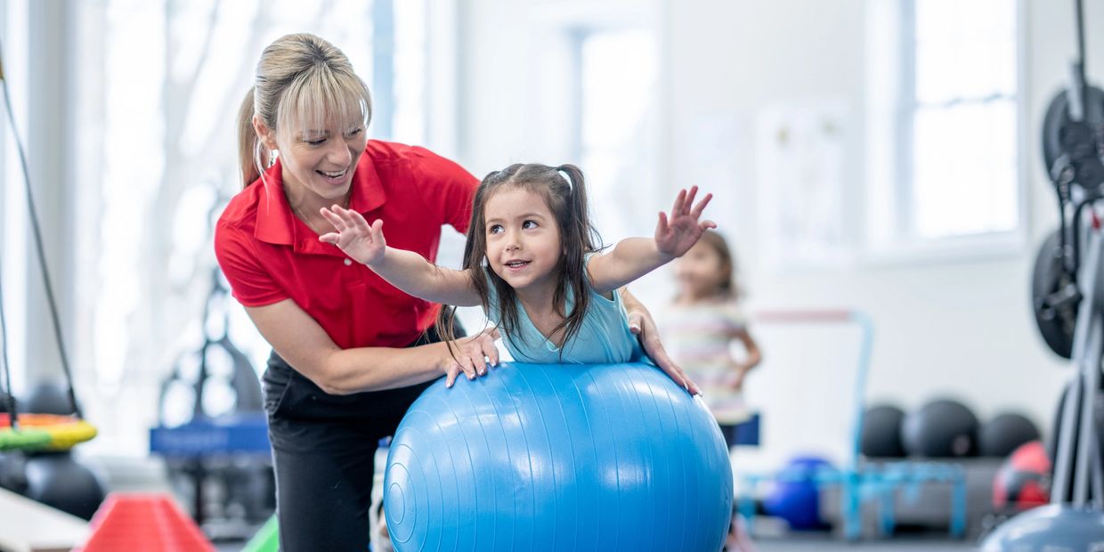 A physiotherapist providing fun and gentle treatment for a child using a therapy ball. 