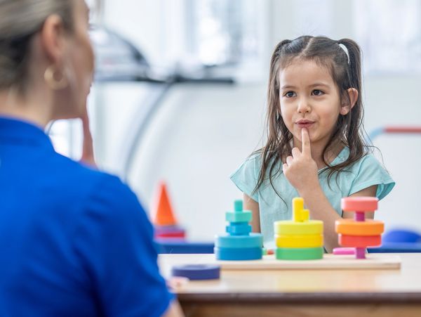 A young girl thoughtfully playing with colorful stacking toys.