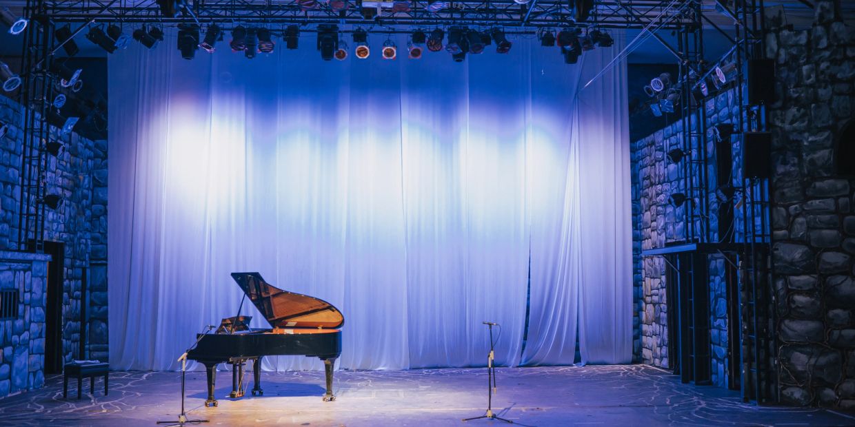 Empty stage with grand piano and microphones.