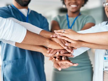 Group of diverse professionals joining hands in unity and teamwork.