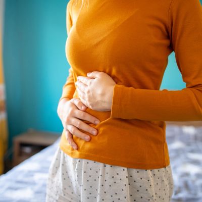 Person holding their stomach, possibly experiencing discomfort.