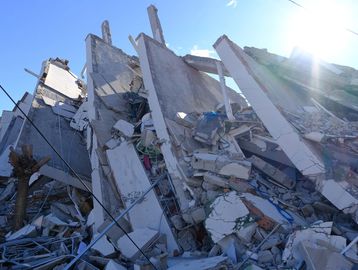 Collapsed building rubble under bright sun.