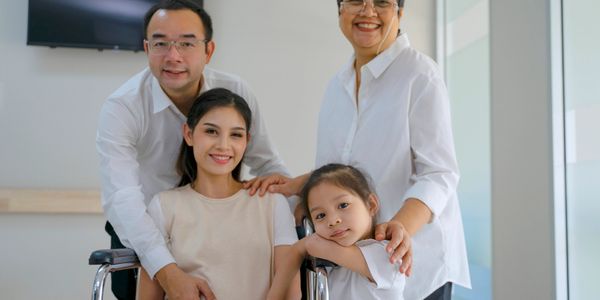 A joyful family gathered around a pregnant woman in a wheelchair.