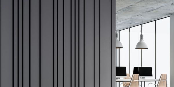 Modern office space with computers and pendant lights near large windows.