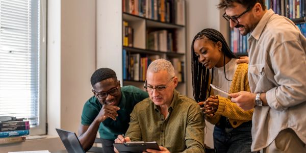 Group studying together around a tablet in a library.