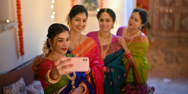 Four women in traditional attire taking a selfie indoors.