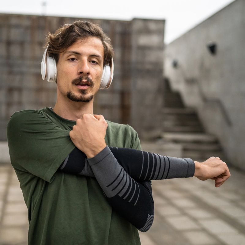 One man modern caucasian male stretch outdoor before training wear green shirt and mustaches and beard young adult recreational activity