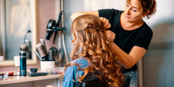 Hairdresser styling a woman's curly hair.