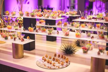 Elegant display of colorful appetizers in a sophisticated setting with purple lighting.
