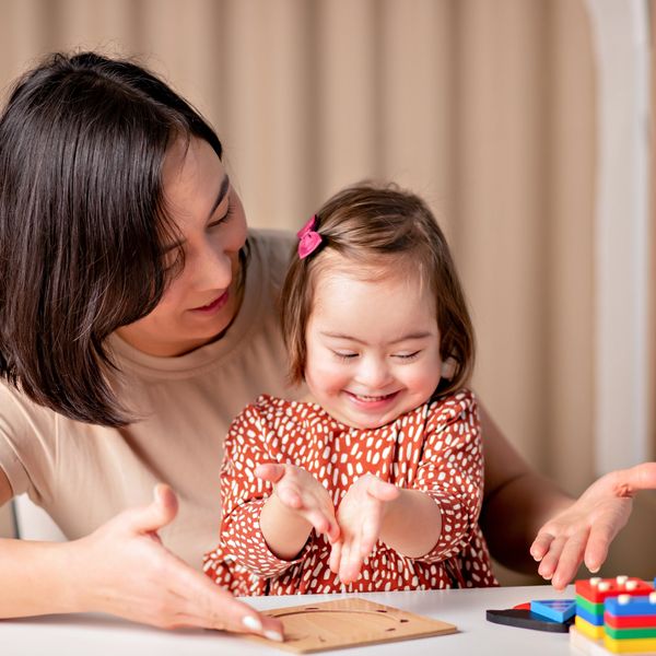 Mother playing puzzle with happy child with Down syndrome.