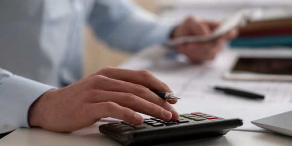Person using calculator with a pen in hand.