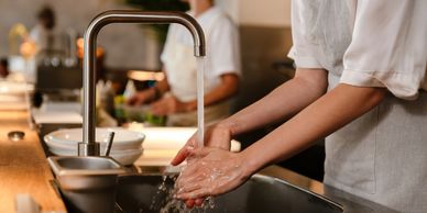 Chef adding sauce to gourmet dishes in a restaurant kitchen.