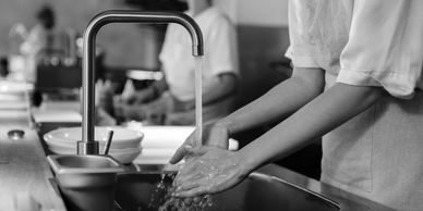 Chef adding sauce to gourmet dishes in a restaurant kitchen.