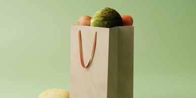 A paper bag filled with fresh vegetables against a green background.