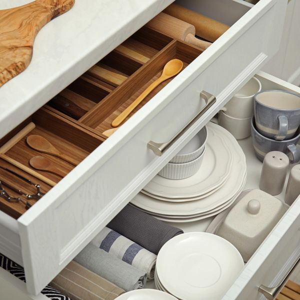 Organized kitchen drawers with utensils, plates, and cups.