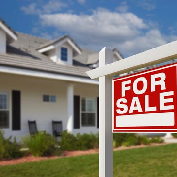 Red and white "For Sale" sign in front of a house with a porch.