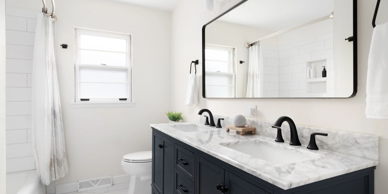 Bright modern bathroom with marble countertop and black fixtures.