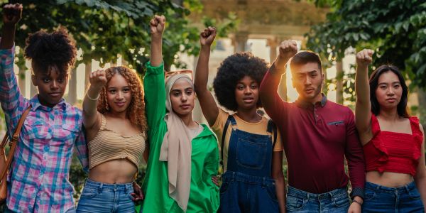 Diverse group raising fists together outdoors.