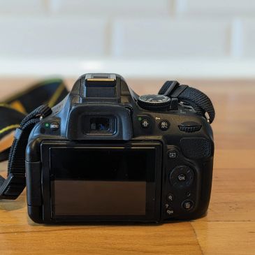 Back view of a DSLR camera on a wooden surface.