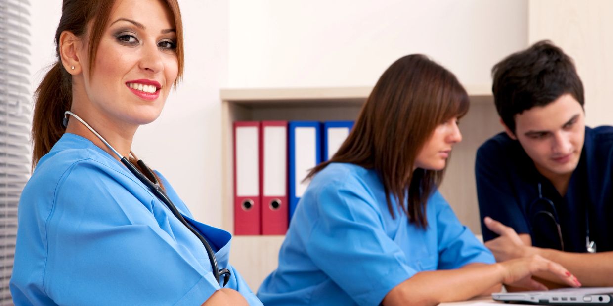 Smiling nurse with colleagues in discussion.