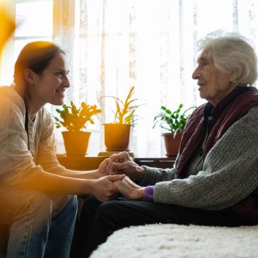 A young woman holding hands with an elderly woman, sharing a warm moment.