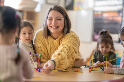 Teacher smiling while doing science activity with kids.
