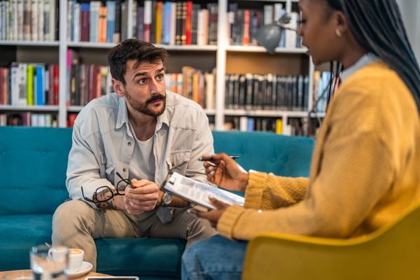 A man attentively listens to a therapist during a session.