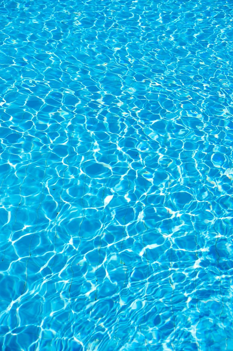 Sunshine and rippled surface of a swimming pool create blue reflections in a sunlit pool that generate patterns and shapes, Aqaba, Jordan