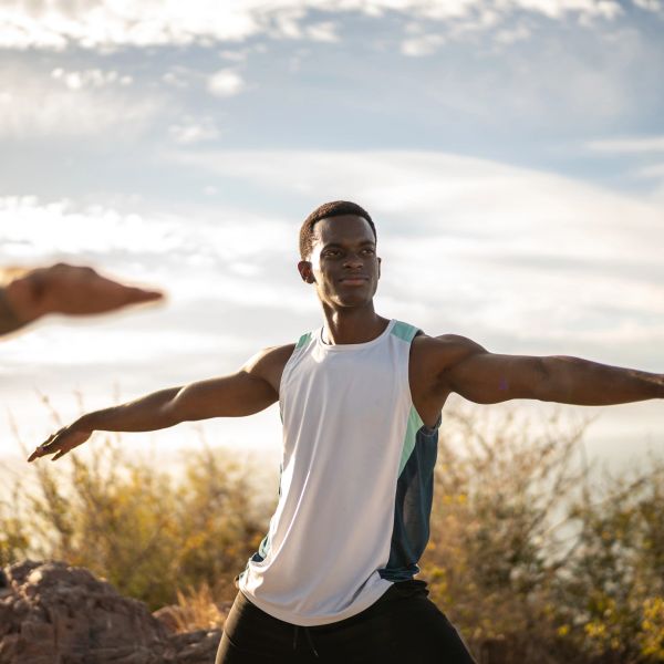 Man practicing yoga outdoors with arms outstretched.