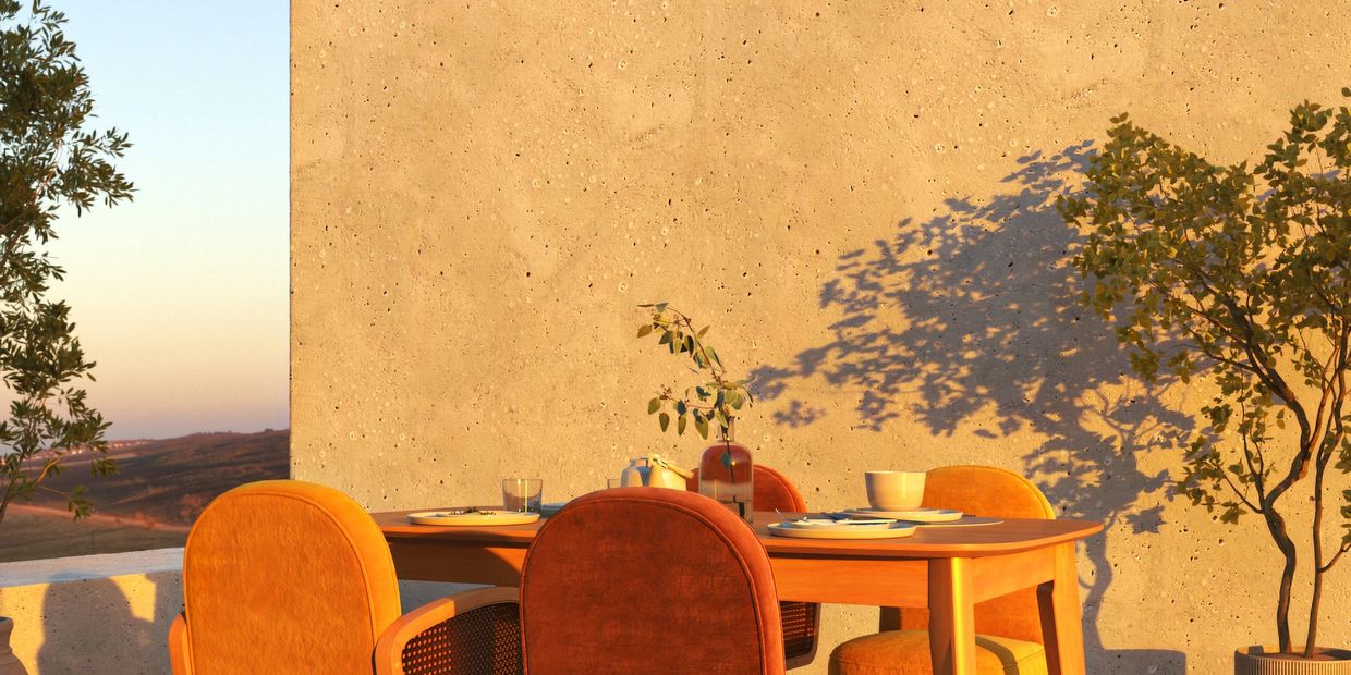 Outdoor dining set with warm-toned chairs and a wooden table in golden hour light.