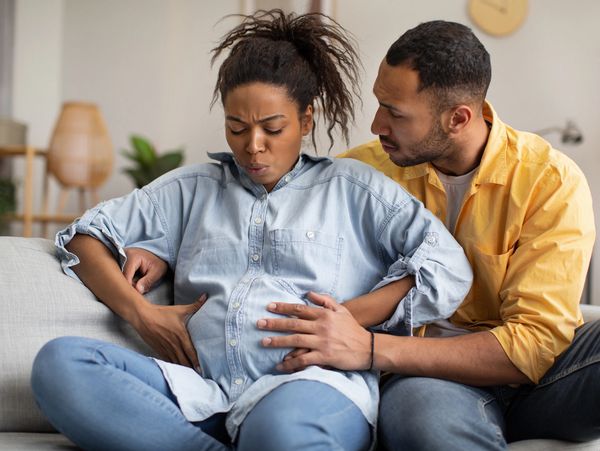 Pregnant woman experiencing labor pains with supportive partner beside her.