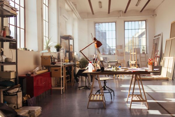 Bright art studio with tables, supplies, and large windows.