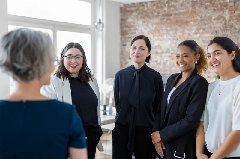Group of businesswomen having meeting in open plan office. Female business professionals are discussing work standing in office.