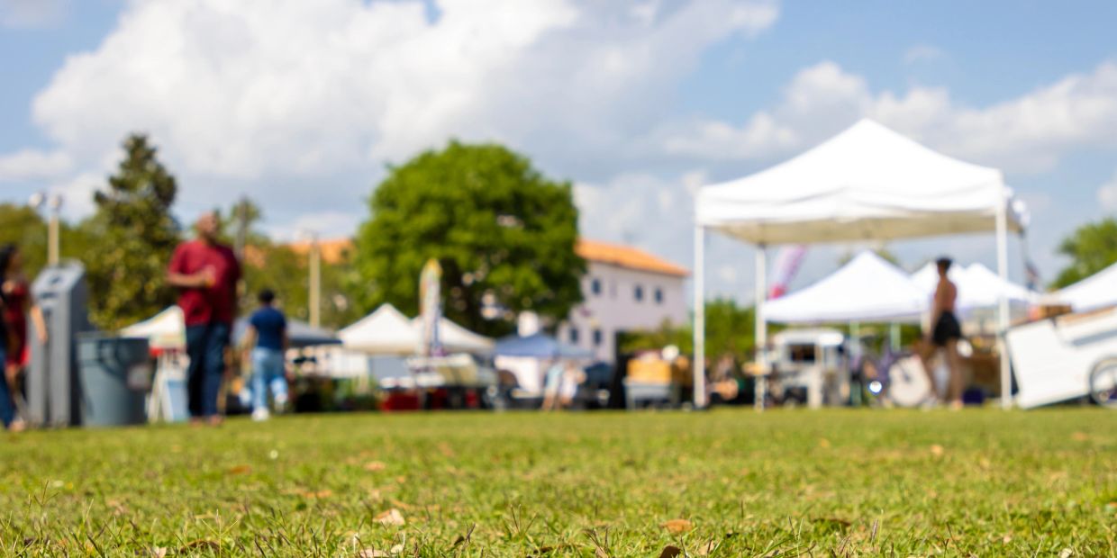 Outdoor event with tents and people on a grassy field.