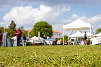 Outdoor market with tents and people on a sunny day.