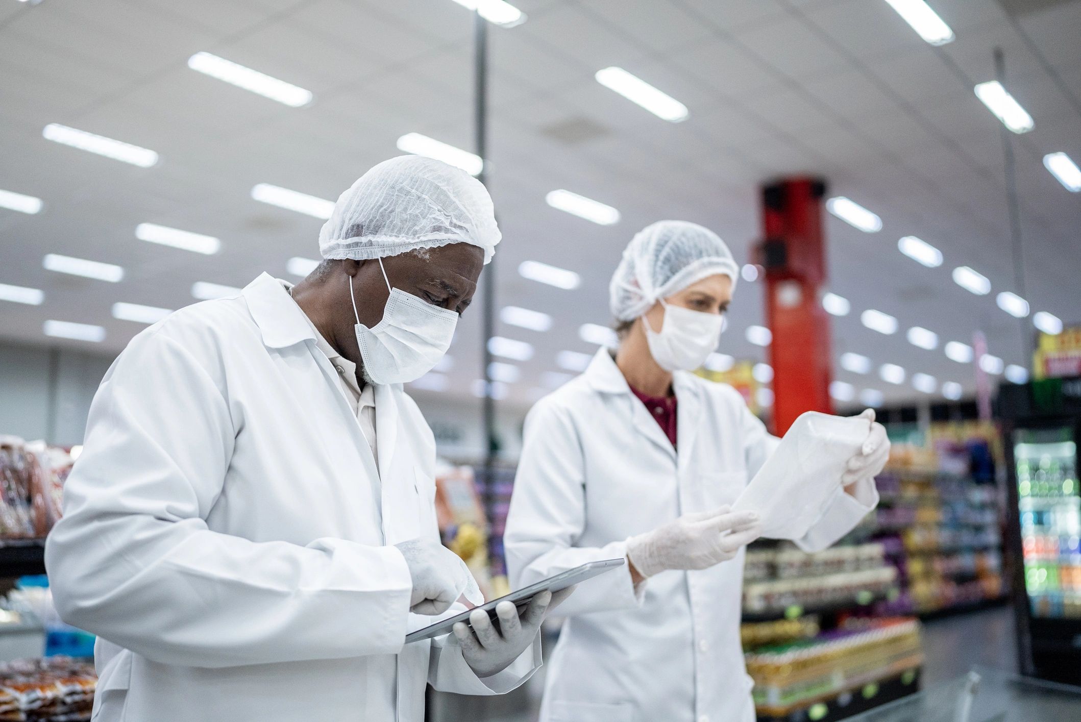 Workers inspecting products in a store wearing protective gear.