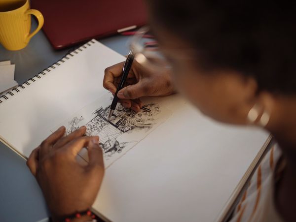 Person sketching detailed artwork in notebook.