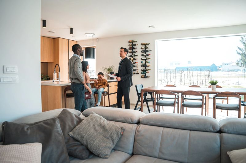 Diverse family buying a new house. Asian male real estate agent giving a diverse family with one child a house tour.