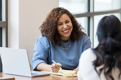 Woman smiling during a conversation at a desk.
