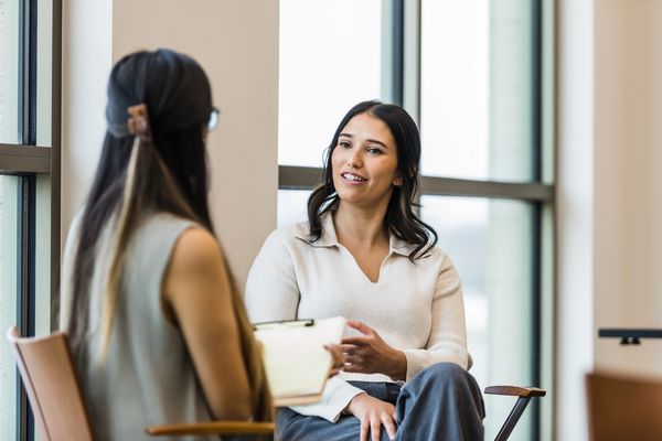 Two women having a professional conversation in a bright room.