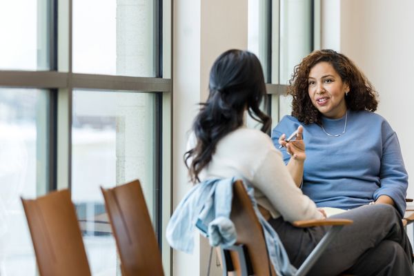 Two women discussing a topic in a bright, modern office space.